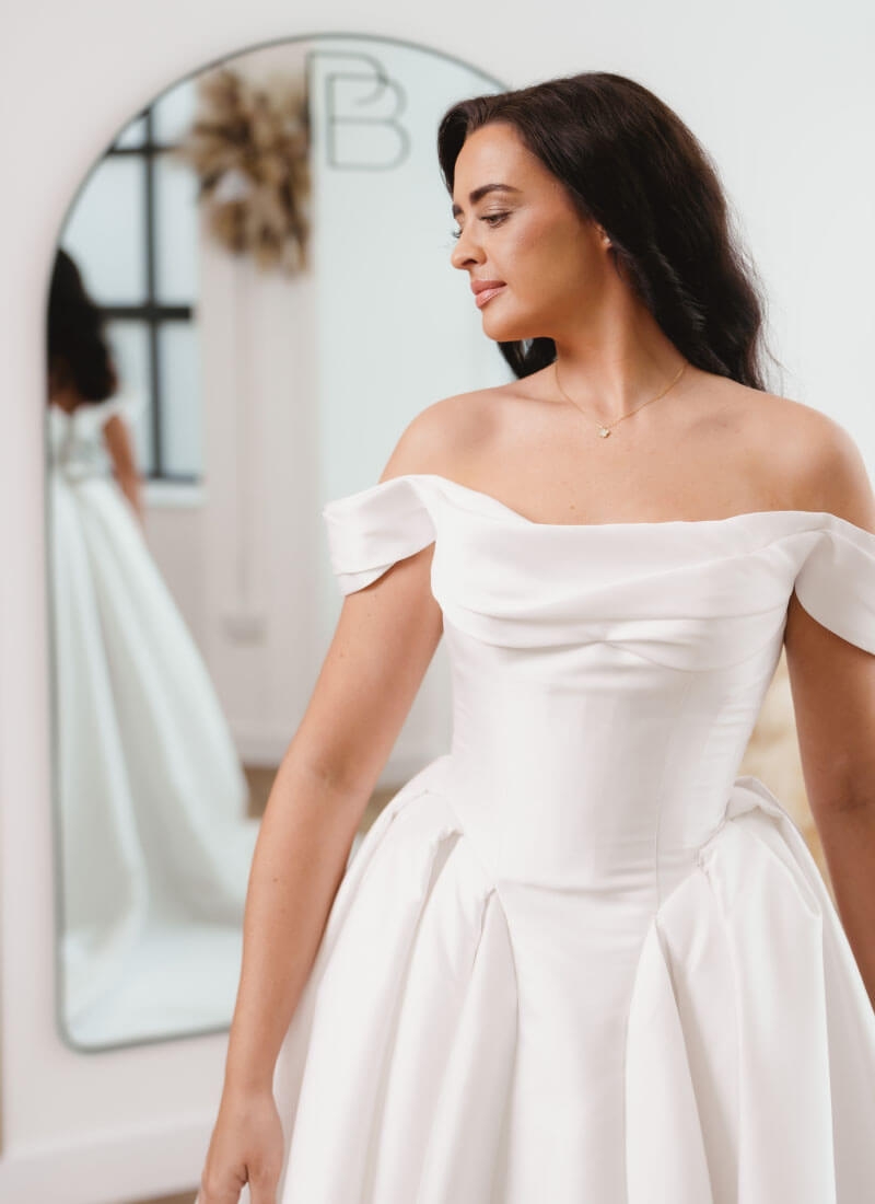 Model wearing a white bridal gown near a mirror