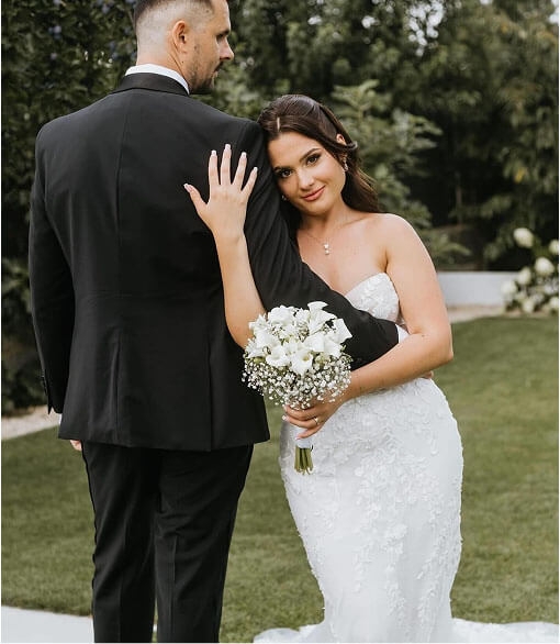 Сouple wearing a white gown and a black suit with flowers