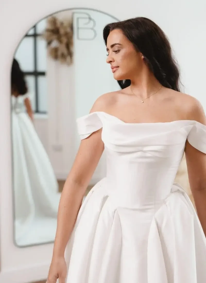Model wearing a white bridal gown near a mirror